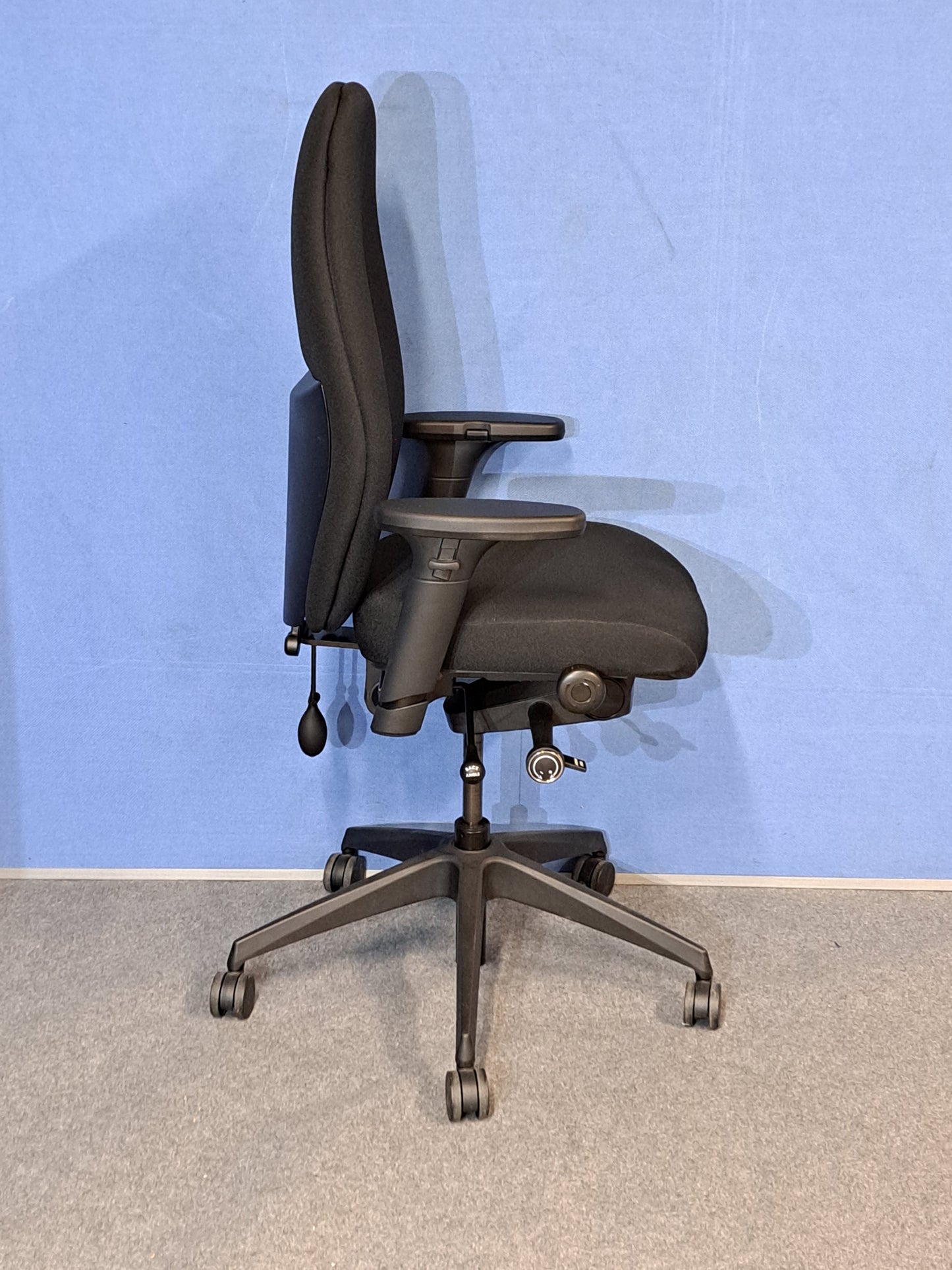 Black office chair on a blue wall and grey carpet