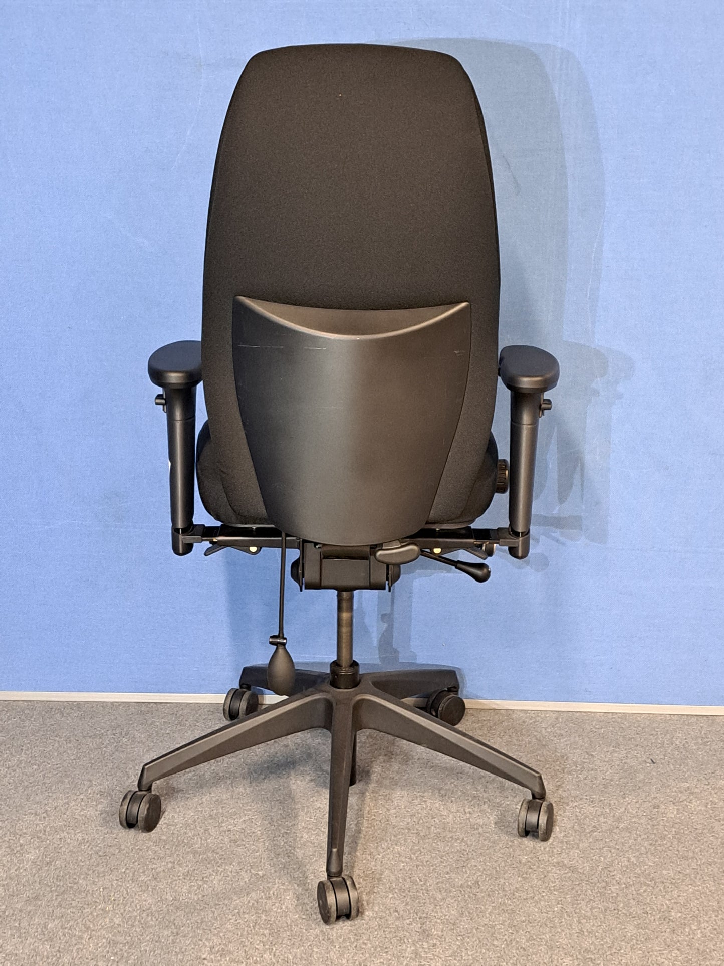 Black office chair on a blue wall and grey carpet