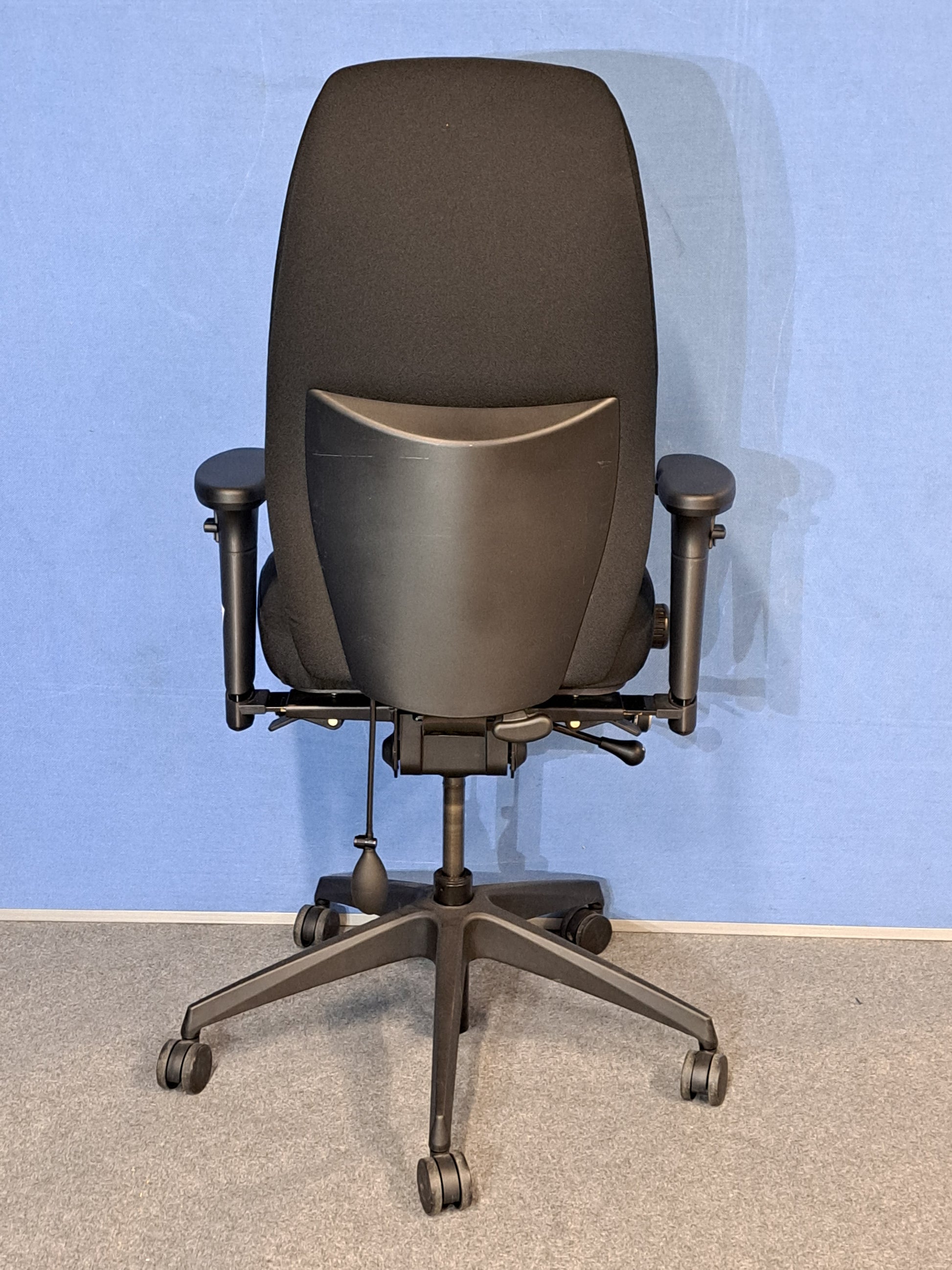 Black office chair on a blue wall and grey carpet