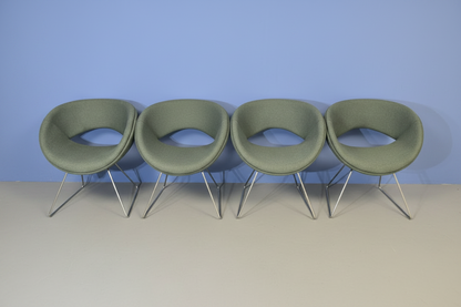 4 green chairs on a blue wall and grey floor