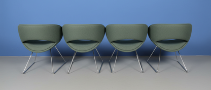 4 green chairs on a blue wall and grey floor