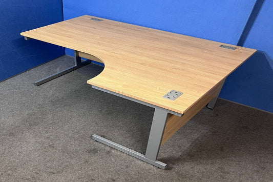 Wooden desk with curved design on a gray floor against a blue wall