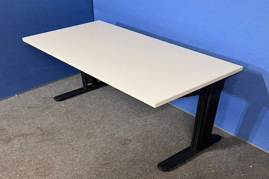 Beige desk with black legs against a blue wall