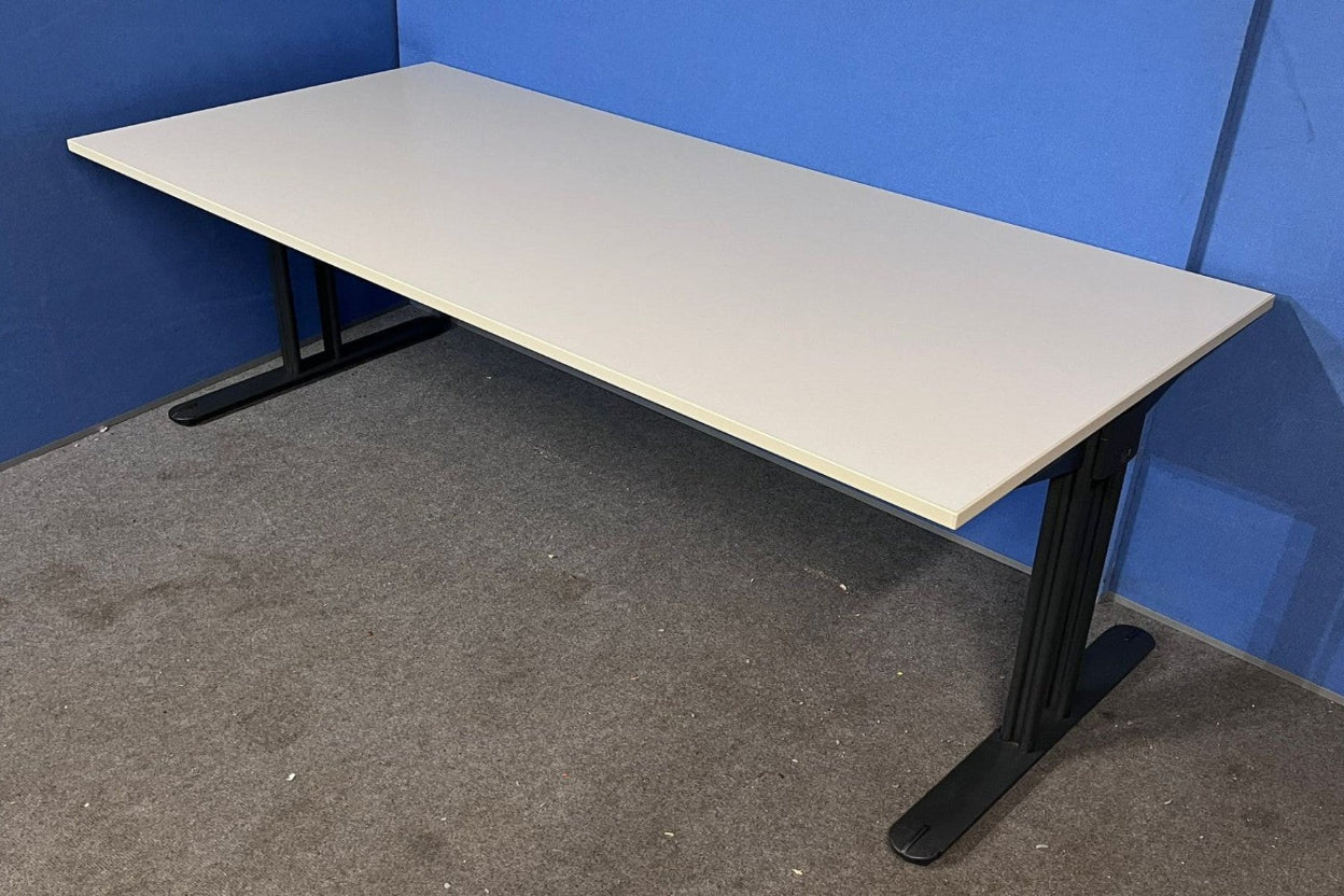 Beige desk with black metal legs against a blue wall.