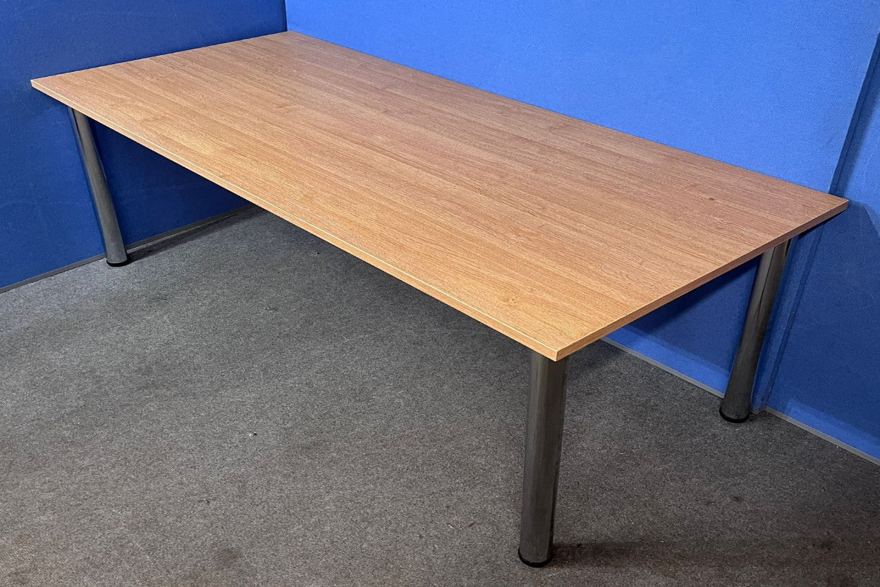Wooden desk with black legs against a blue wall.