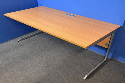 Wooden desk with metal legs against a blue wall.