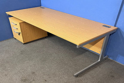 Wooden office desk with drawers against a blue wall.