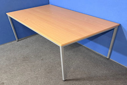 Wooden desk with metal legs against a blue wall.