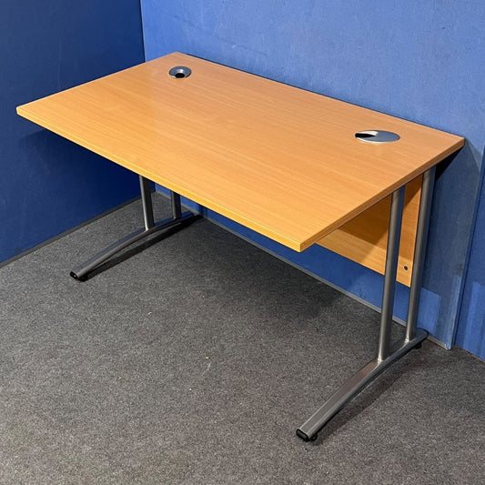 Beech straight desk against a blue wall and grey floor