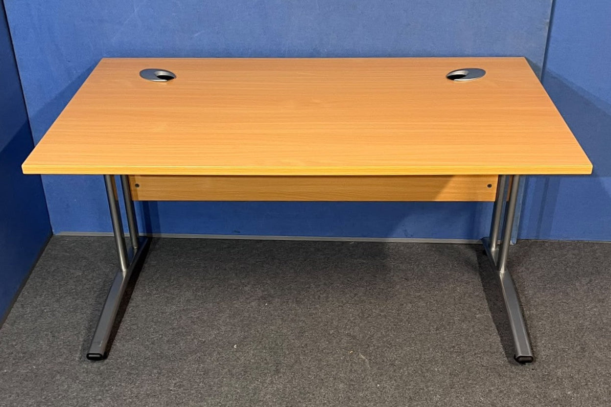 Beech straight desk against a blue wall and grey floor