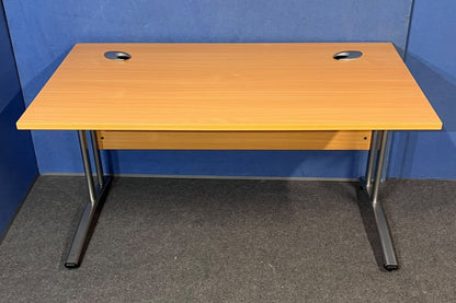 Beech straight desk against a blue wall and grey floor