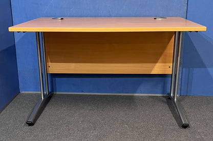Beech straight desk against a blue wall and grey floor