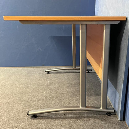 Beech straight desk against a blue wall and grey floor