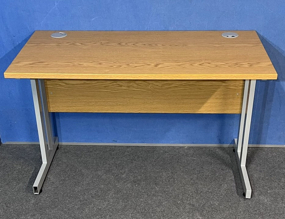 Oak straight desk on a blue wall and grey carpet