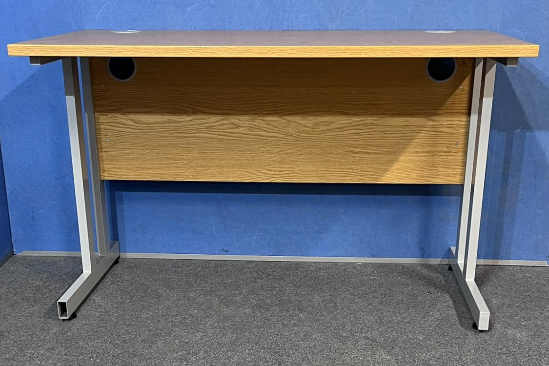 Oak straight desk on a blue wall and grey carpet