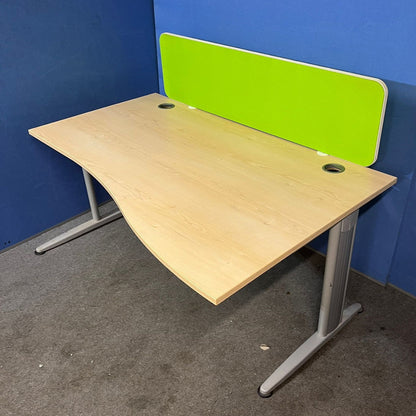 Wooden desk with a green partition against a blue wall.
