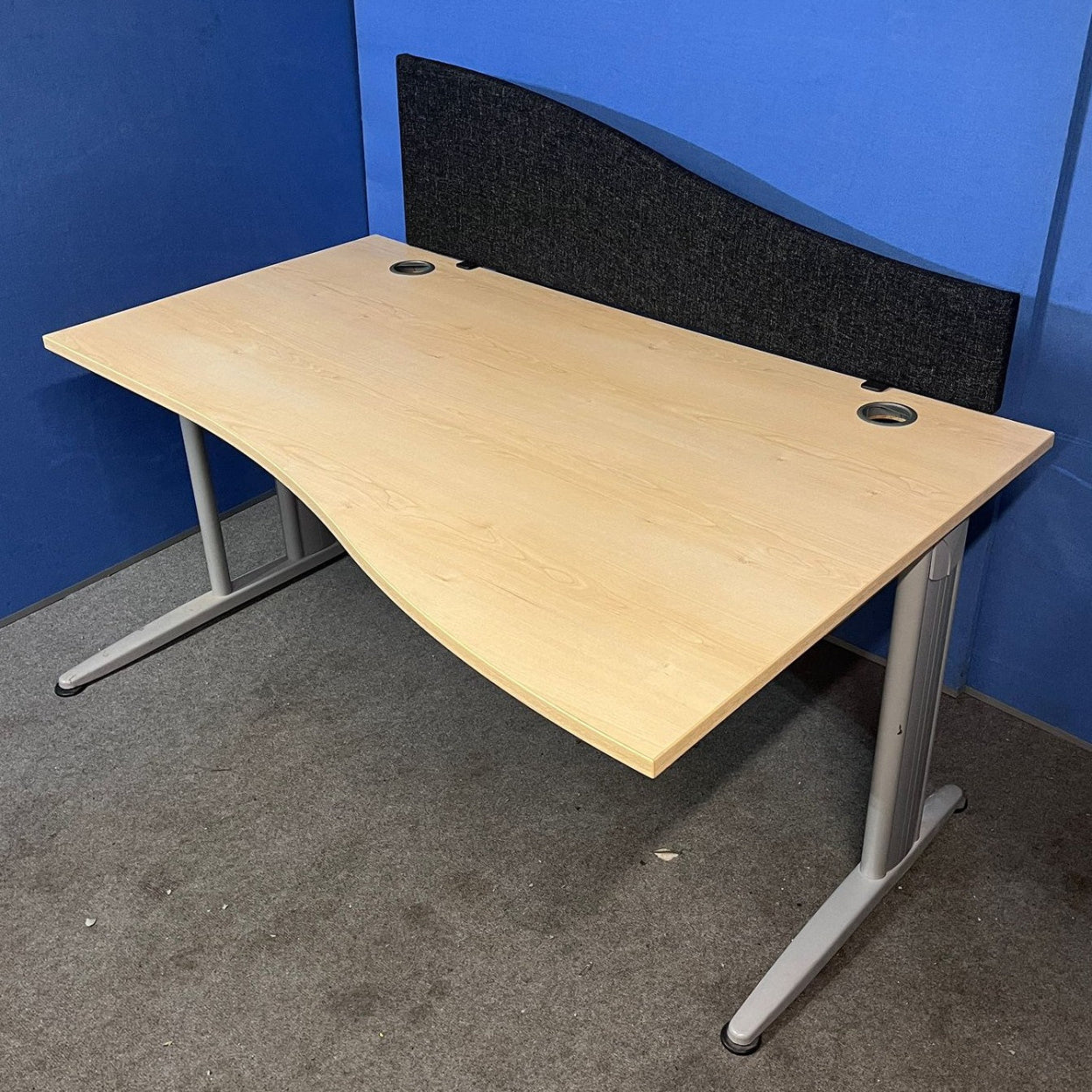Wooden office desk with a black screen against a blue wall