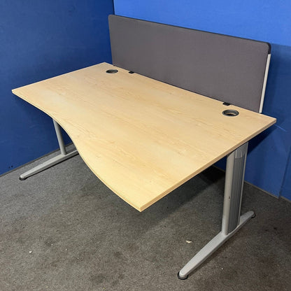 Wooden office desk with a gray partition against a blue wall.