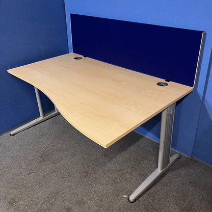 Wooden desk with a blue screen partition against a blue wall.