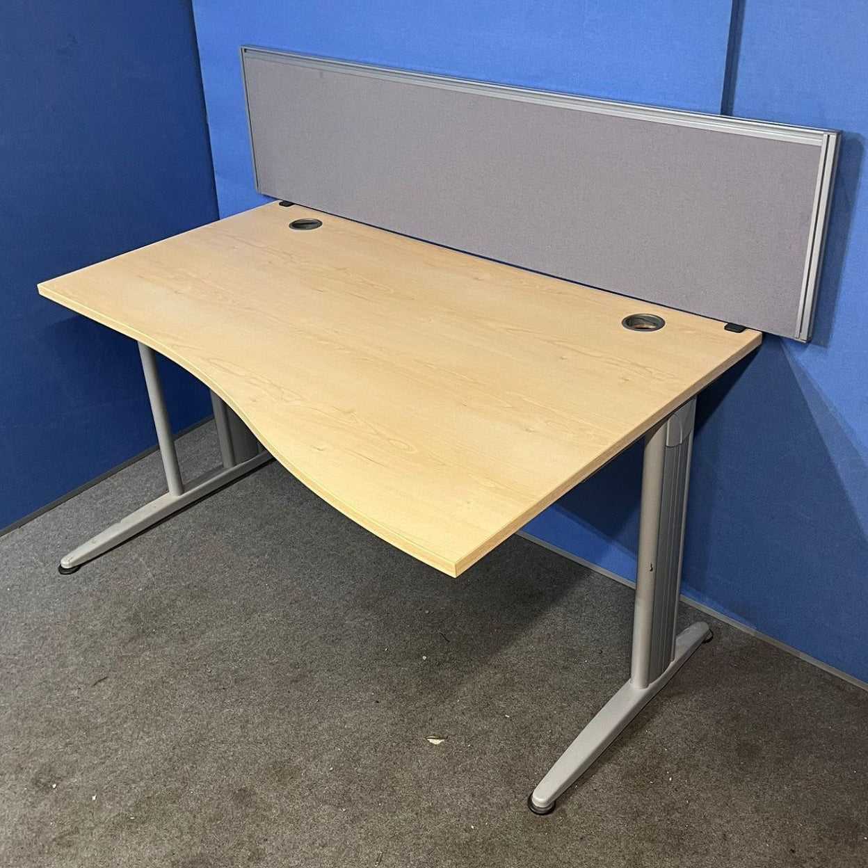 Wooden desk with a gray screen against a blue wall