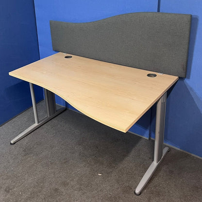 Wooden office desk with a gray partition against a blue wall.