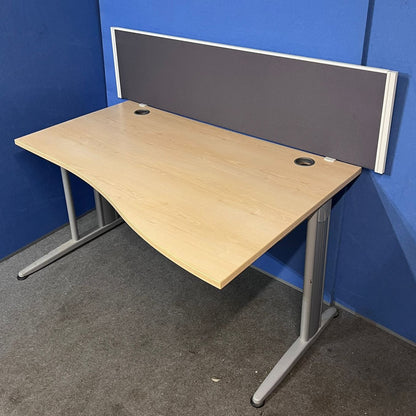 Wooden office desk with a gray partition against a blue wall.
