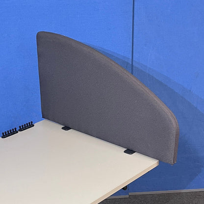 Gray fabric desk screen attached to a beige desk against a blue wall.