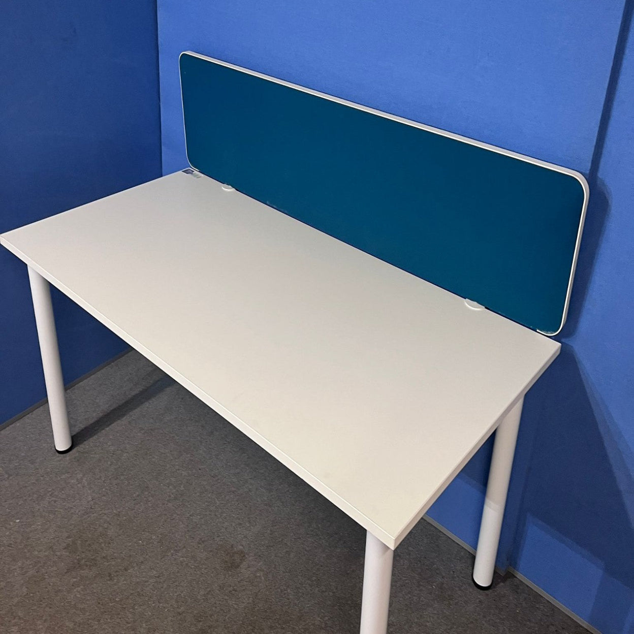White desk with a blue screen against a blue wall