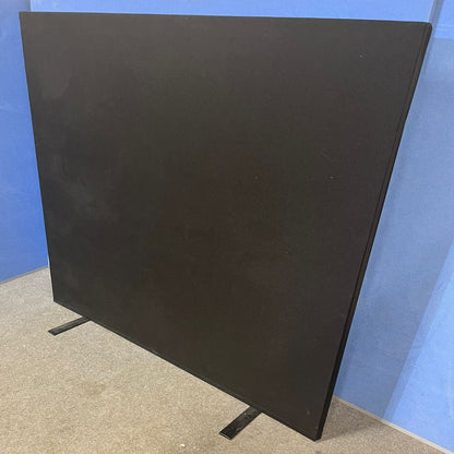 Black freestanding screen against a blue wall