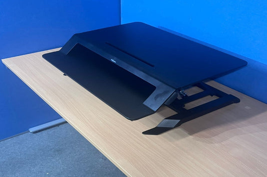 Blue adjustable laptop stand on a wooden desk against a blue wall