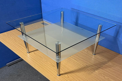 Glass coffee table with metal legs on a wooden floor against a blue wall