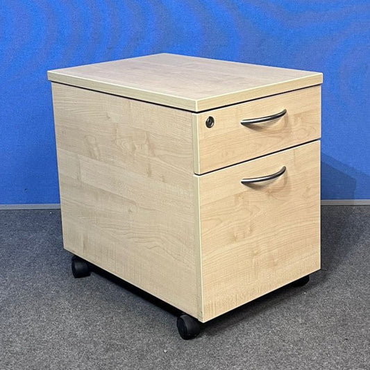 Wooden pedestal with two drawers on wheels against a blue wall.