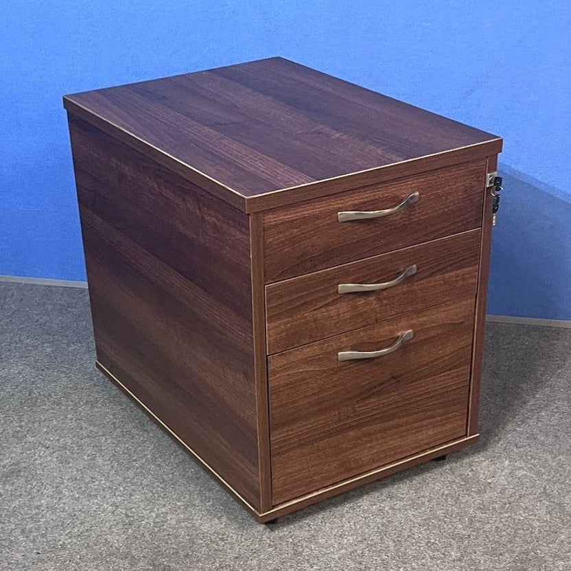 Wooden pedestal with three drawers against a blue wall.