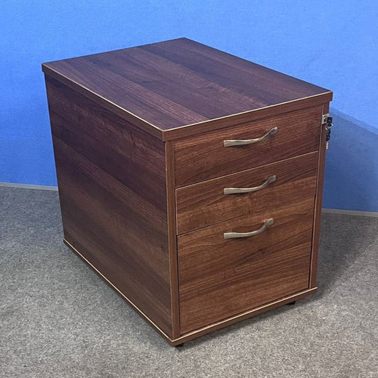 Wooden pedestal with three drawers against a blue wall.