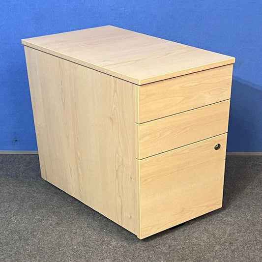 Wooden pedestal with two drawers against a blue wall.