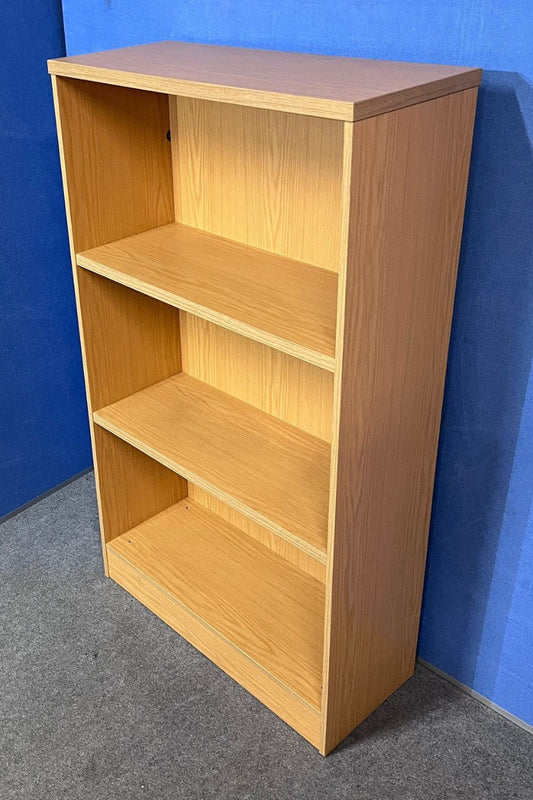 Wooden bookshelf with three shelves against a blue wall.