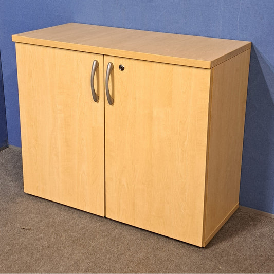 Wooden cabinet with two doors against a blue wall.