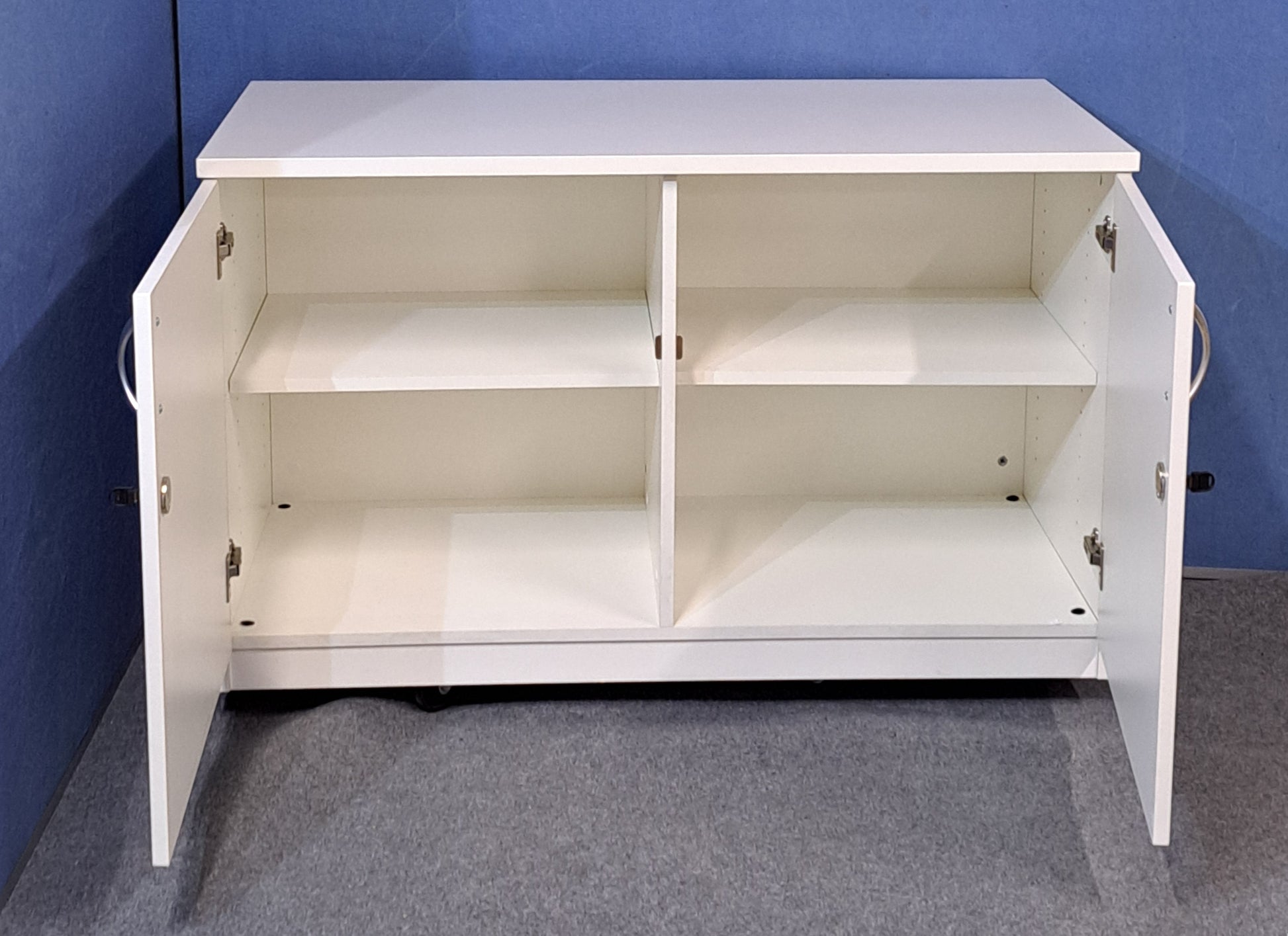 White cabinet with silver handles against a blue wall