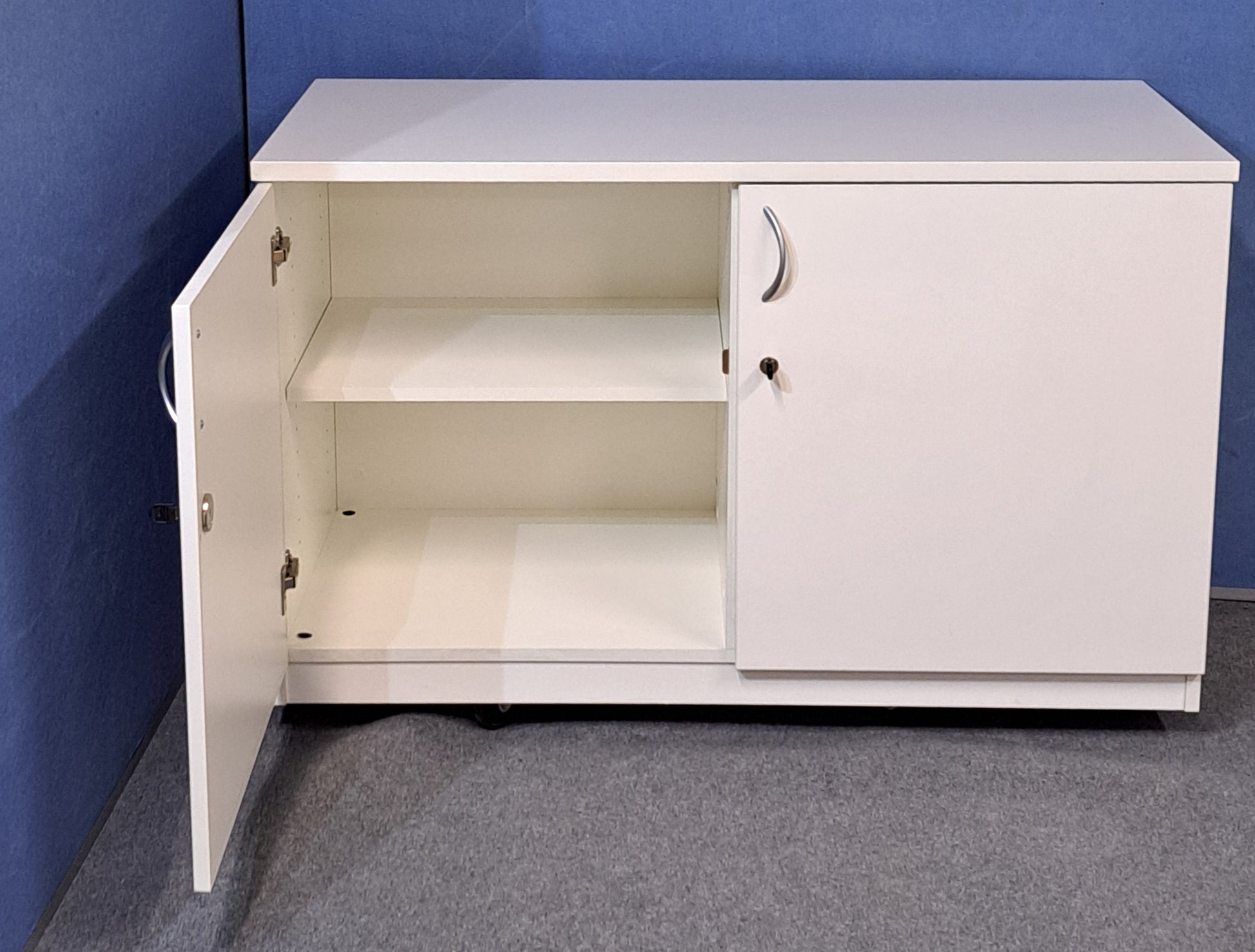 White cabinet with silver handles against a blue wall