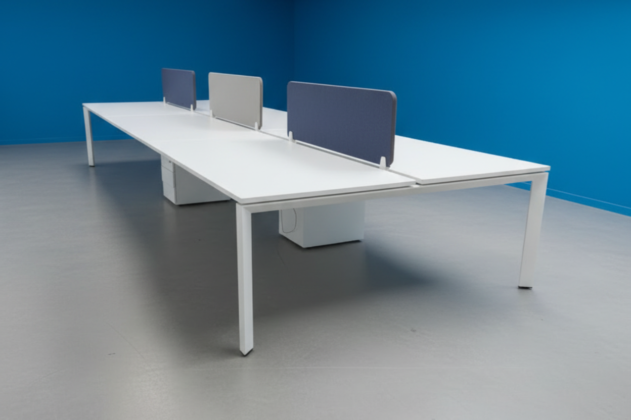 Modern office desk with partition screens against a blue wall.