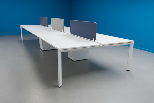 Modern office desk with partition screens against a blue wall.