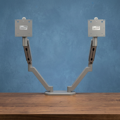 Monitor arms on a walnut desk with a subtly textured blue background