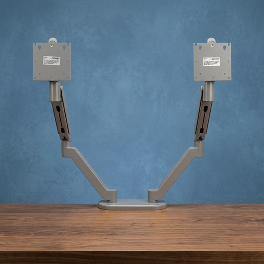 Monitor arms on a walnut desk with a subtly textured blue background